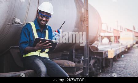 African engineer technician wearing a helmet, groves and safety vest for repair the train with using tablet Stock Photo