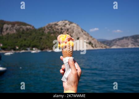 Ice cream cone held up to the hot summer sky. Female hand holding ice cream cone. Vanila ice cream Stock Photo