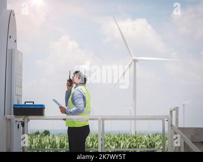 Engineer man is using a tablet to control and monitor the operation of a wind turbine in the electrical control room.Concept of sustainability develop Stock Photo