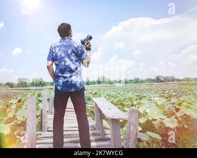 The traveler man holding the camera and standing on the old bridge with appreciating the beauty of nature.Travel and photography concept Stock Photo