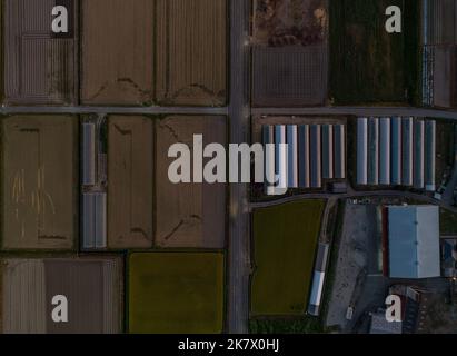 Top-down view of unplanted fields and greenhouses on farm at dusk Stock Photo