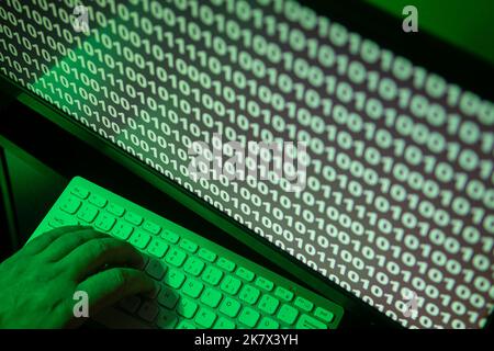hand on keybord with binary code on a screen, green illuminated Stock Photo