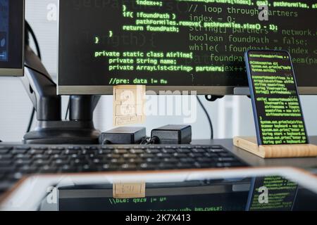 Close up of programmers workplace with computers keyboard and green code lines on screen Stock Photo