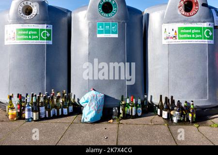 Bottle and Glass Banks three full containers and wine botlles many with caps arranged outside the bins Stock Photo