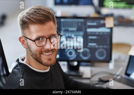 Close up portrait of young software developer smiling at camera and wearing glasses in office, copy space Stock Photo