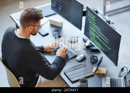 High angle view at software developer writing code while using computer and data systems in office Stock Photo
