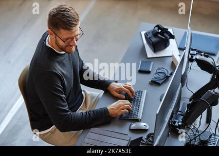 Top view at smiling software developer writing code while using computer and VR systems in office Stock Photo