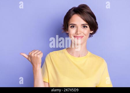 Portrait of pretty positive person indicate thumb finger empty space isolated on purple color background Stock Photo