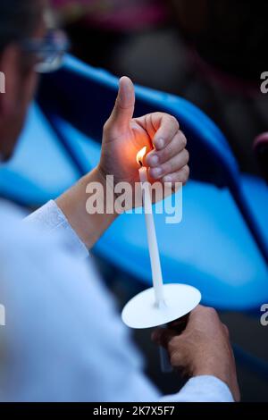 Man holding lit candle outdoors Stock Photo