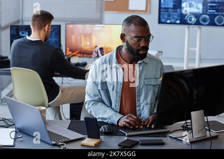 Portrait of black man using computer while writing software code in office, copy space Stock Photo