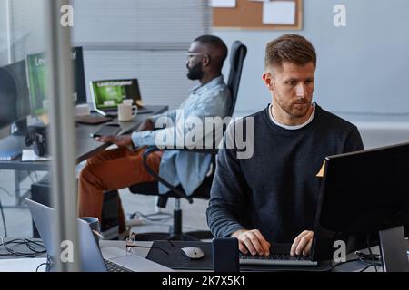 Portrait of young Caucasian man using computer while working with data analysis in IT, copy space Stock Photo