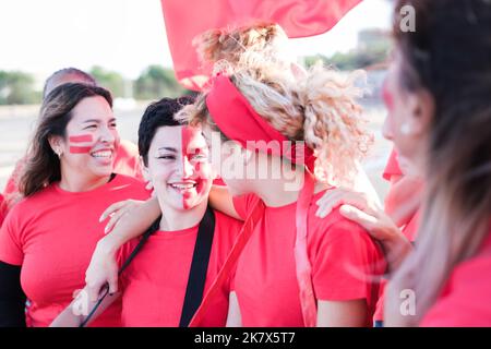 Two young women look at each other with affection at their team's outdoor fan meeting Stock Photo