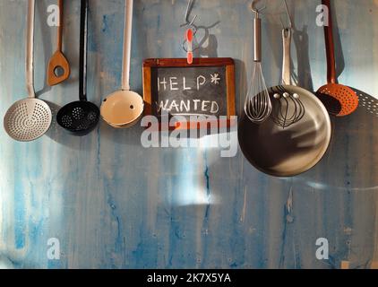 Help wanted sign,restaurant or cafe looking for staff after corona lockdown, kitchen utesnils and message on blackboard Stock Photo