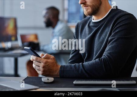 Side view closeup of man using smartphone at workplace while working in mobile software development Stock Photo