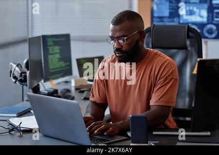 Portrait of black software engineer using computer in high technology office, data systems and programming concept, copy space Stock Photo