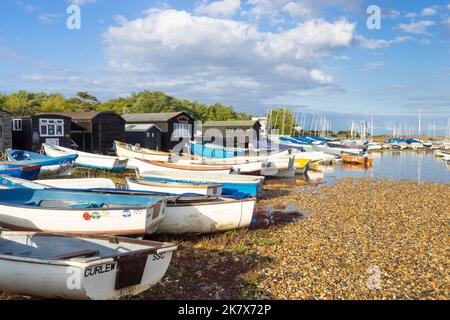 Boats moored in front of the Fishermens' huts and Riverside Tearoom on the shingle beach of the River Alde at Orford Suffolk England UK Europe Stock Photo