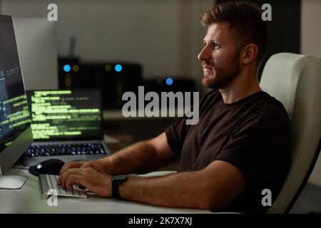 Portrait of young man programming software at workplace in dim night light Stock Photo