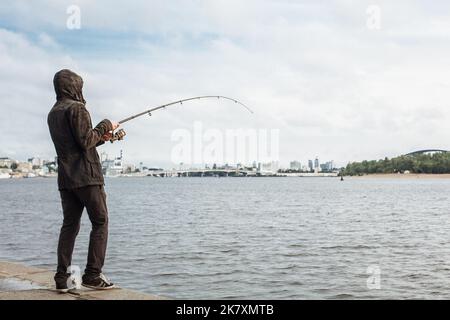 Young man fishing with a spinning on the river Stock Photo