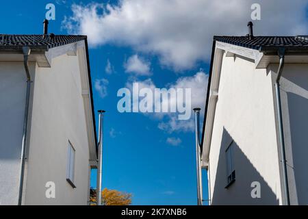 View of stainless steel chimneys between two houses in front of blue sky with white clouds. Stock Photo