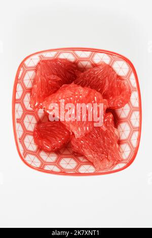 juicy red grapefruit slices on a small plate, top view Stock Photo