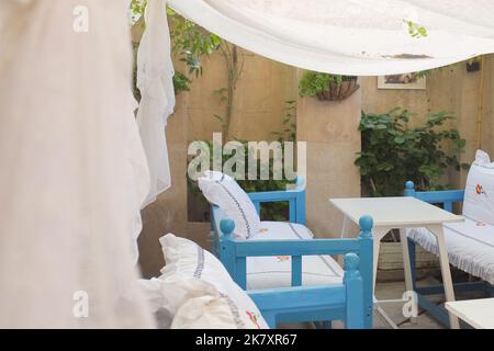 Inside Arabian Tea House, a pretty quaint local cafe in Al Fahidi Dubai, UAE. Blue benches with white cushions and sheer canopy are like outdoor beds. Stock Photo