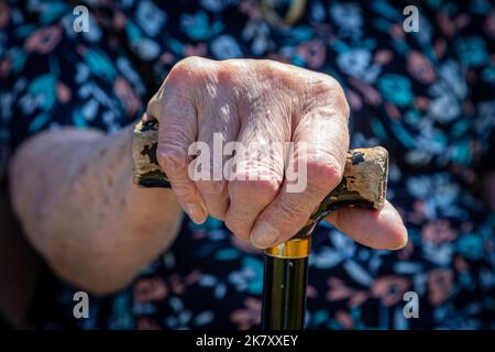 A close up of a womans hand holding a walking stick, with a shallow depth of field Stock Photo