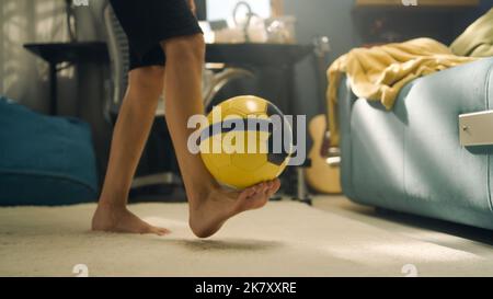 Boy plays football on the carpet alone in his room. Kicking the ball. Preparing for the school football match. Sports, soccer, leisure, hobby concept. Stock Photo