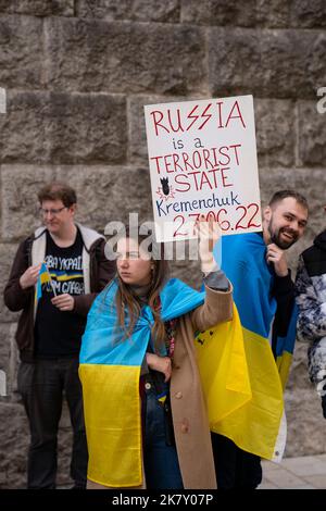 Birmingham, UK. 15th Oct, 2022. Ukrainian supporters demonstrating against RussiaÕs invasion and occupation of Ukraine outside Birmingham Town Hall, West Midlands, United Kingdom.  Girl with flag draped over her shoulders, holding ÔRussia is a terrorist state, KremenchukÕ poster. Credit: NexusPix/Alamy Stock Photo