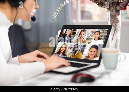 Young having conversation with her colleagues during video call Stock Photo
