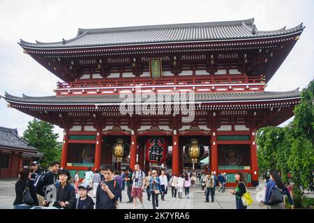 View of Hozomon Gate inside Sensoji temple complex with crowd of people walking and clouds in bright sky background. Stock Photo