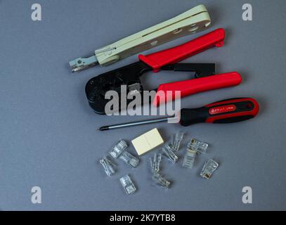 Hand crimp tool for crimping of the round terminals and small heap of blue insulated terminals on a white background Stock Photo