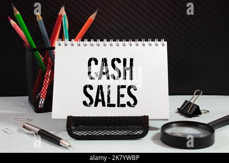 On the table there is a red marker and a white paper tablet on which the text is written - CASH sales Stock Photo