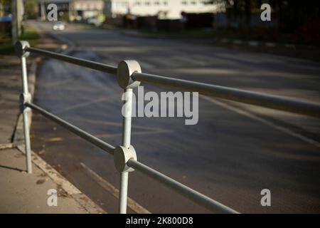 Handrail by road. Pedestrian barrier. Fence along road. Fencing details. Stock Photo