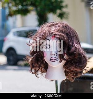 Portrait of a styrofoam woman's head modeling a wig outside of a vintage clothing store. Stock Photo