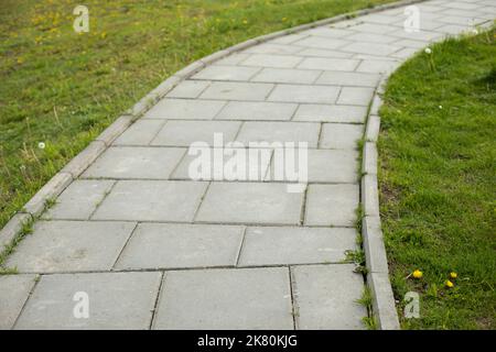 Path in park. Tile trail through park. Details of pedestrian zone. Place for walking. Tiles made of stone. Stock Photo