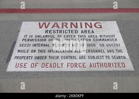 A sign painted near the flight line and runway of a military air force base in the USA emphasizes:  WARNING USE OF DEADLY FORCE AUTHORIZED Stock Photo