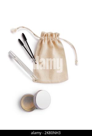 Mockup burlap bag for cosmetics, brushes for combing eyebrows, cream in jar and spray in bottle Stock Photo