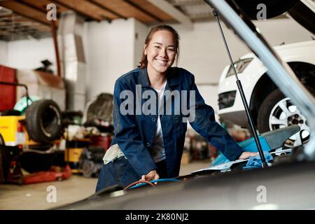 Ill do my best to help get your vehicle back on the road again. a female mechanic working on a car in an auto repair shop. Stock Photo