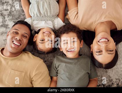 Children, parents and lying on floor from above, happiness spending time together in family home. Mom, dad and young kids smiling on carpet, happy Stock Photo