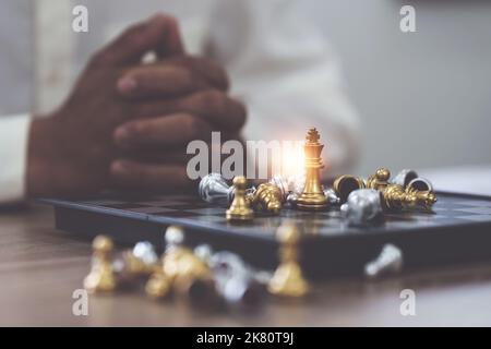 Close up of hands of a business man moving king golden chess to defeat  opponent the chess game is development analysis, strategy, and plan, the  management or leadership concept. 22804709 Stock Photo