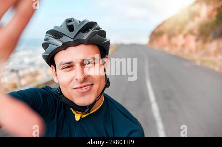 Selfie, fitness and man cycling in the road on the mountains in Switzerland for adventure, peace and freedom. Face portrait of a young, happy and free Stock Photo
