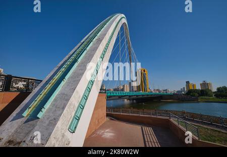 A view of the modern, curved, cable suspended bridge over the Ishim river. In Astana, Nur Sultan, Kazakhstan. Stock Photo