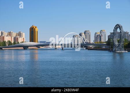 A view of the modern, curved, cable suspended bridge over the Ishim ...