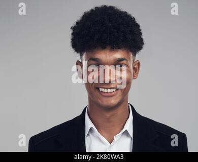 A positive outcome comes from a positive mindset. Studio portrait of a confident young businessman posing against a grey background. Stock Photo