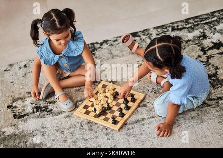 Girl children, knowledge fun and chess game on a living room carpet for home education. Kids in a household for brain development growth, youth Stock Photo