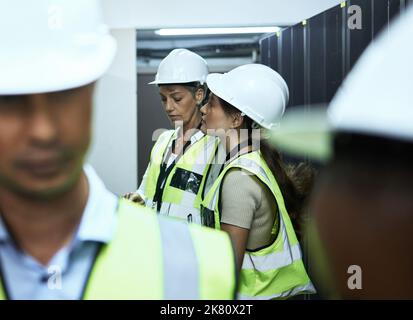 They know what it means to program. a group of computer programmers working in a server room. Stock Photo