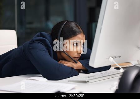 I just want to give up on this work. a young businesswoman looking bored while working on a computer in a call centre. Stock Photo