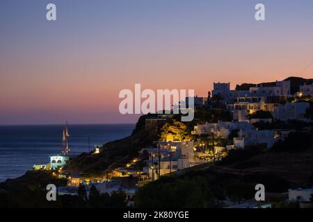 Ios, Greece - September 6, 2022 : Breathtaking purple sunset and view of the illuminated picturesque hotels and restaurants at the Mylopotas beach in Stock Photo