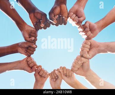 Fist hands, circle and diversity support human rights people, protest group and freedom of racism on blue sky background. Below solidarity Stock Photo