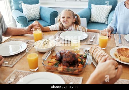 Food, family and praying with girl at a table, holding hands in gratitude, prayer and bonding before eating. Worship, pray time and child looking Stock Photo